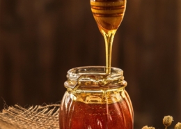 runny honey dripping from spurtle into jar