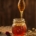 runny honey dripping from spurtle into jar