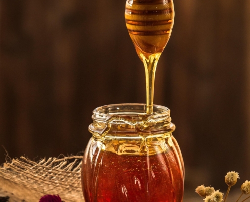 runny honey dripping from spurtle into jar