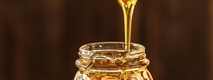 runny honey dripping from spurtle into jar