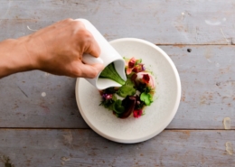 Green herb dressing being poured over salad