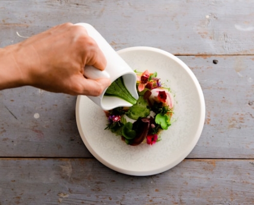 Green herb dressing being poured over salad