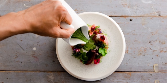 Green herb dressing being poured over salad