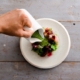 Green herb dressing being poured over salad