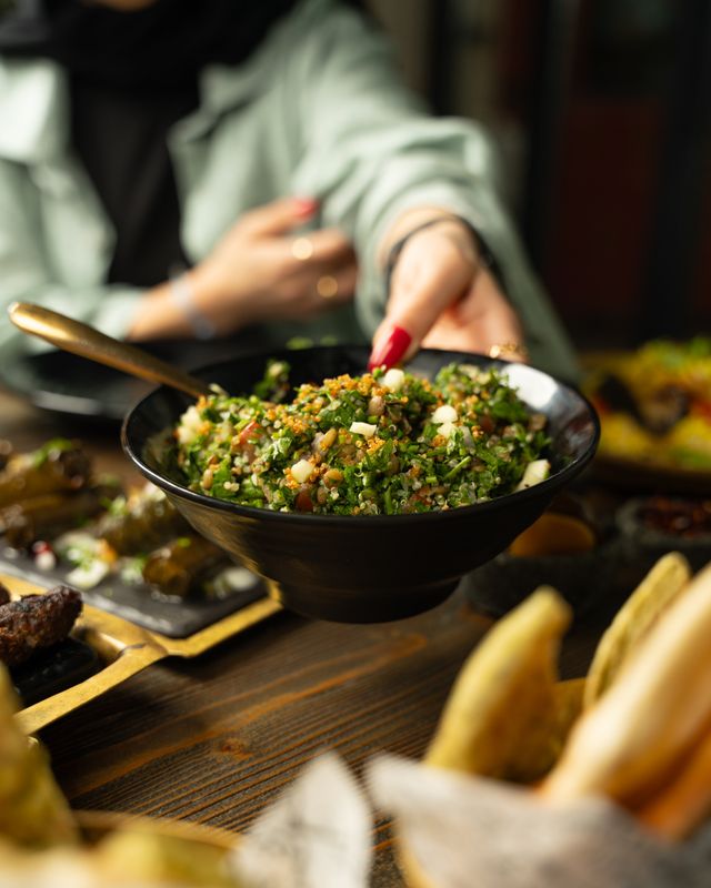 Someone passing a bowl of tabbouleh